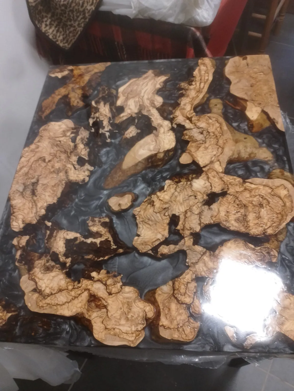 Piano di un tavolo in legno e resina nera, visto dall’alto